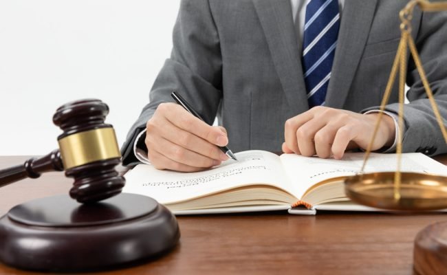 closeup-shot-person-writing-book-with-gavel-table